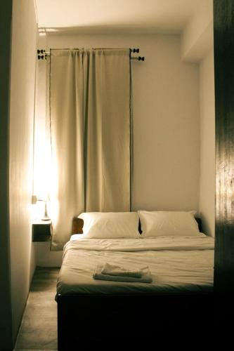 a bedroom with a bed with white sheets and a window at R and H Stay in Kohīma
