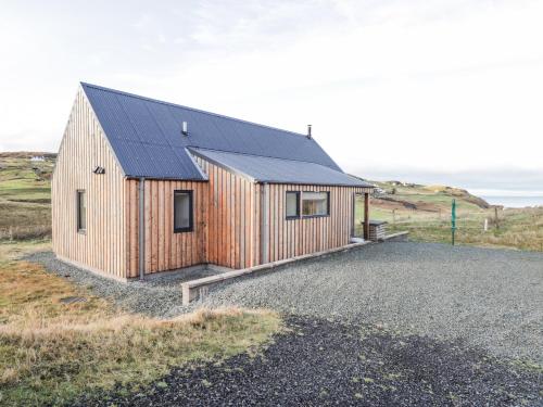 a wooden house with a solar roof on a field at Skye Falls Chalet in Milovaig