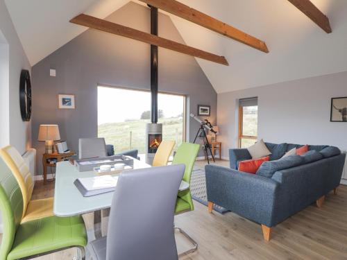 a living room with a couch and a table at Skye Falls Chalet in Milovaig