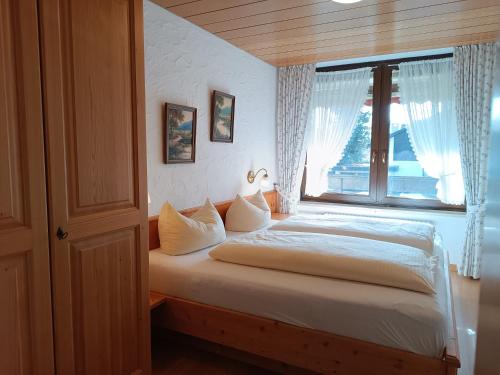 a bedroom with a bed with a large window at 2-Raum FeWo Arnika - Hallenbad & Sauna in Fischen