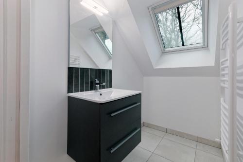 La salle de bains est pourvue d'une coiffeuse noire et d'un lavabo. dans l'établissement Le Logis de la Vicomté - Maison proche plage, à Dinard