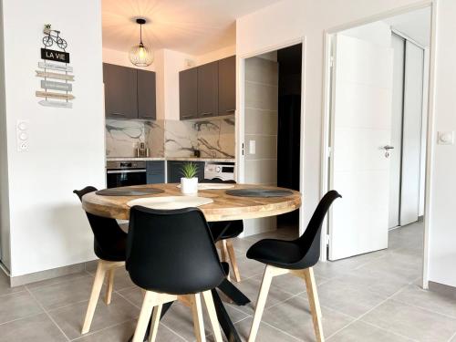 une cuisine avec une table en bois et des chaises noires dans l'établissement Brand new flat with terrace and parc view, à Nice