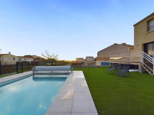 - une piscine avec de l'herbe verte à côté d'un bâtiment dans l'établissement À 350m de la plage, maison pour 7 avec piscine, à Bretignolles-sur-Mer