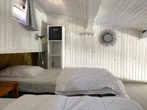 une chambre avec deux lits et un miroir au mur dans l'établissement Appart clim wifi - 2 à 6 pers - piscines - parking, à Fitou