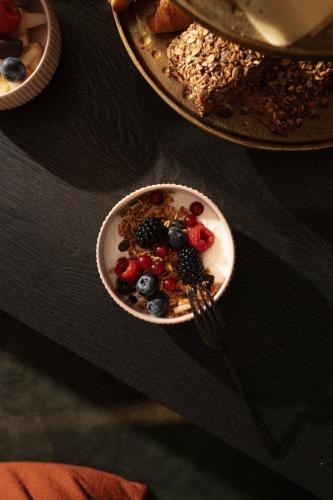 a bowl of cereal and berries on a table with a fork at Boutiquehotel Le Foulage - adults only in Bruges