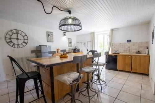 une cuisine avec un îlot et des tabourets de bar dans l'établissement La maison de lolo et marco pour 6, à Champagnac-de-Bélair