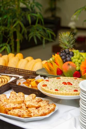 a table topped with plates of food and fruit at Le Village Flats e Hotel in Joinville