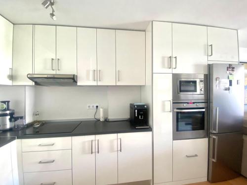 Una cocina con gabinetes blancos y un refrigerador de acero inoxidable. en Casa Valdes Los Cristianos Center, en Los Cristianos