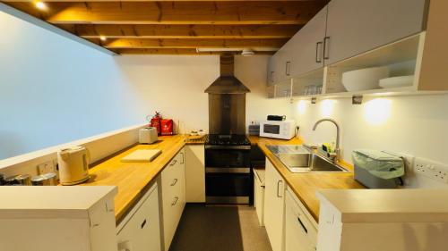 a kitchen with white cabinets and a stove top oven at Afan Forest BunkHouse - Gallery Apartment in Glyncorrwg