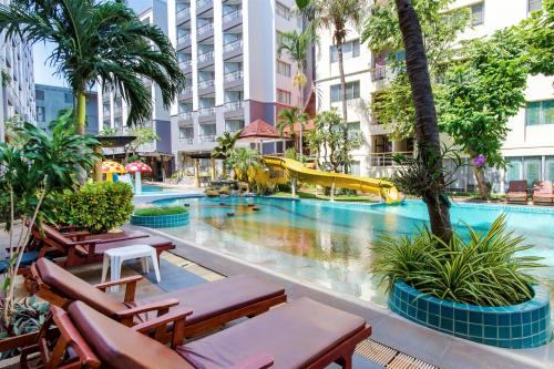 a pool at a hotel with chairs and a slide at Hua Hin First-Hin Nam in Hua Hin