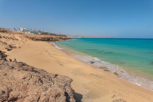 a beach with rocks and the ocean on a sunny day at Casa del mar in Costa Calma