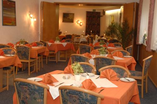 a dining room with orange tables and chairs at Hotel-Restaurant zum Roeddenberg in Osterode