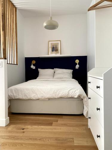 une chambre avec un grand lit avec une tête de lit noire dans l'établissement La Petite Paroisse, à Versailles