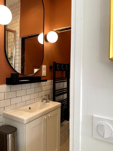 une salle de bain avec un lavabo et un miroir dans l'établissement La Petite Paroisse, à Versailles
