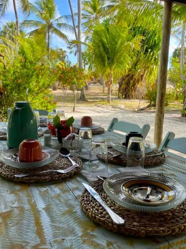 a table with plates and utensils and palm trees at Barrinha dos Ventos Barrinha de Baixo Ceara Quartos Casas Kitesurf in Acaraú
