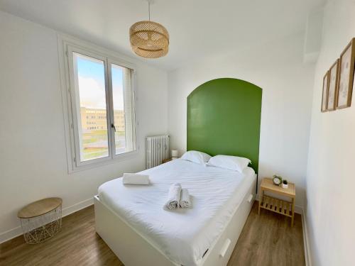 - une chambre avec un grand lit blanc et une tête de lit verte dans l'établissement Spacieux Appartement 3 chambres Au Pied De La Gare, à Amiens