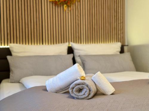 a towel sitting on top of a bed with pillows at Bergling Apartment im Zentrum • Netflix • Festungsblick • Obst und Wein • in Königstein an der Elbe