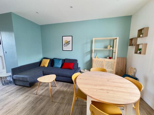 un salon avec un canapé bleu et une table dans l'établissement Spacieux Appartement 3 chambres Au Pied De La Gare, à Amiens