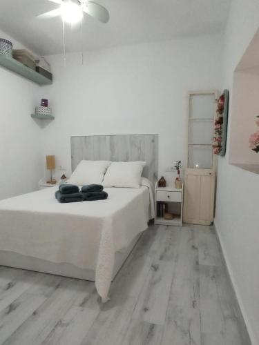 a bedroom with a white bed and a wooden floor at Casa Encarnita in Arcos de la Frontera