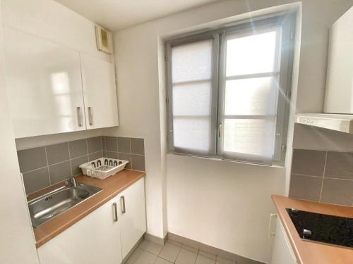 une cuisine avec un évier et une fenêtre dans l'établissement Appartement service - Vue sur le Musee - Paris 5 - FLAT-GUEST, à Paris