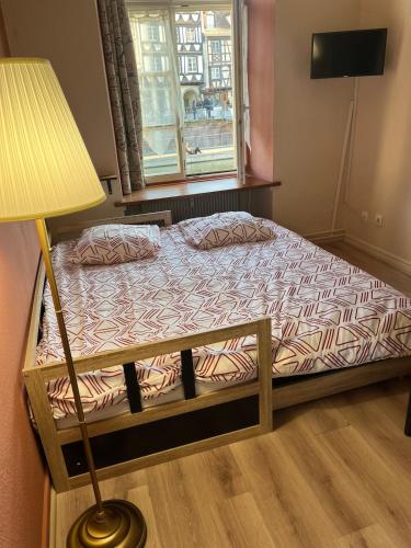 Ce lit se trouve dans un dortoir doté d'une lampe et d'une fenêtre. dans l'établissement À la belle étoile, à Strasbourg