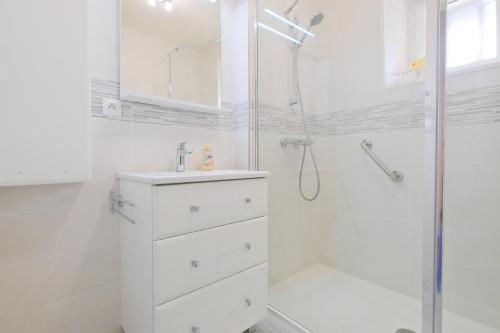 une salle de bain blanche avec une douche et un lavabo dans l'établissement Maison de Campagne, Grande Métairie, à Villetoureix