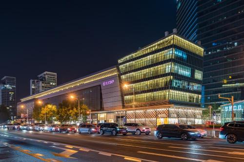 a city street with cars parked in front of a building at Dequan Luxury HotelGuomao BranchThe subway is right outside the door Coffee, fruits, snacks, a gym and a laundry room are provided for free in the lobby in Beijing