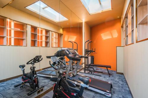 a gym with three bikes in a room with orange walls at Dequan Luxury HotelGuomao BranchThe subway is right outside the door Coffee, fruits, snacks, a gym and a laundry room are provided for free in the lobby in Beijing