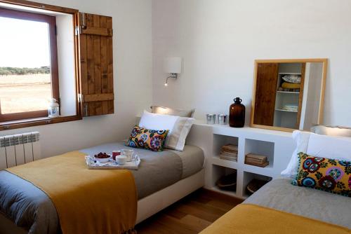 a bedroom with two beds and a window at Montadinho Houses in São Bartolomeu da Serra