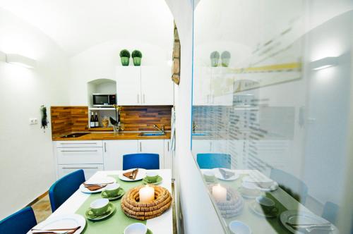 a white kitchen with a table and blue chairs at Séd Pince Vendégház in Somlójenő