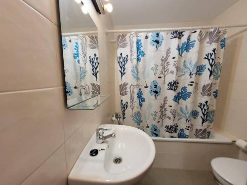 a bathroom with a sink and a shower curtain at FGDR34 1H "Cala Prellezo" in San Vicente de la Barquera