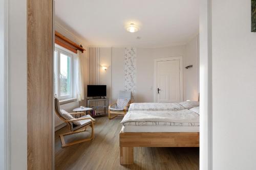 Un dormitorio con una cama y una silla y un televisor. en Ole Post, en Dagebüll