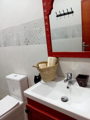 a bathroom with a sink and a mirror and a toilet at taghoba surf house in Tamraght Ouzdar