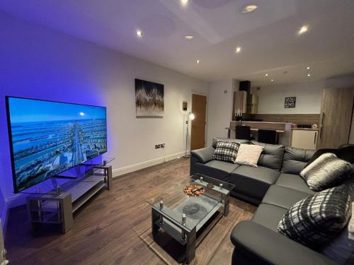 a living room with a couch and a large flat screen tv at 24-7 Secured City Centre Apartments with Free Underground Parking and WiFi in Birmingham