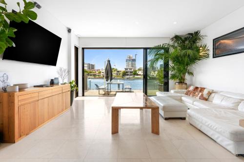 a living room with a white couch and a tv at 3 m Luxury Waterfront Villa in Paradise Pets Welcome in Gold Coast