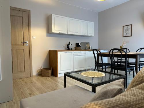 a living room with a table and a kitchen at APARTAMENTY LAVENDERIA z widokiem na Górę Parkową, blisko centrum in Kudowa-Zdrój