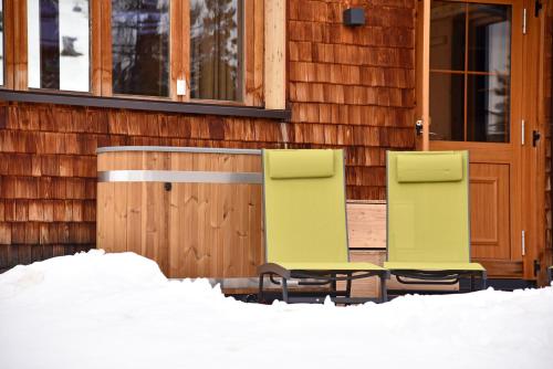 two chairs sitting outside of a house in the snow at Bockspitze Deluxe Appartements in Hinterweisspriach