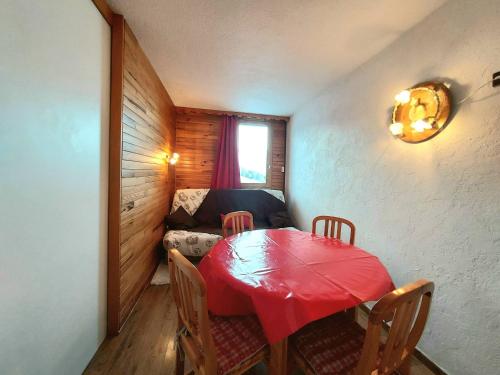 - une salle à manger avec une table rouge et un canapé dans l'établissement Studio au pied des pistes avec balcon et cuisine équipée - Plagne Villages - FR-1-351-158, à La Plagne Tarentaise