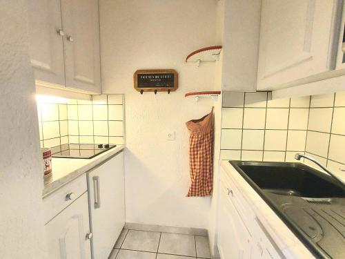 une petite cuisine avec un évier et une horloge murale dans l'établissement Studio au pied des pistes avec balcon et cuisine équipée - Plagne Villages - FR-1-351-158, à La Plagne Tarentaise