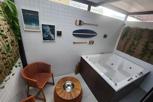 a bathroom with a tub and a chair and a table at Get By Side in João Pessoa