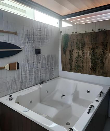 a large white bath tub in a bathroom at Get By Side in João Pessoa