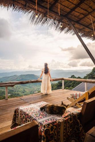 a woman in a white dress standing on a wooden deck at U Garden in Ban Huai Khai