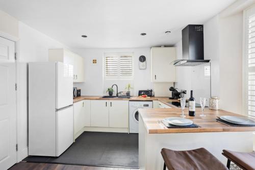 a kitchen with white cabinets and a wooden table at Luxury Holiday Apartments in Torquay