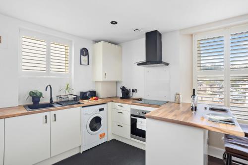 a kitchen with white cabinets and a washer and dryer at Luxury Holiday Apartments in Torquay
