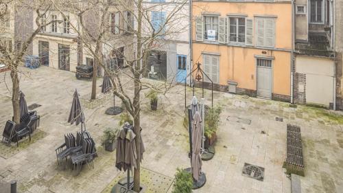 an overhead view of a courtyard with chairs and umbrellas at Le Logis des Perles 2 - Emplacement Idéal - 6 pers in Troyes