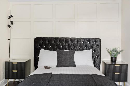 a bed with a black headboard and two night stands at Luxury Holiday Apartments in Torquay