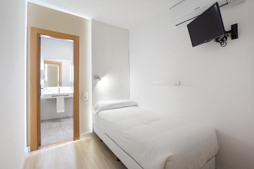 a small bedroom with a bed and a mirror at Atenas Granada in Granada