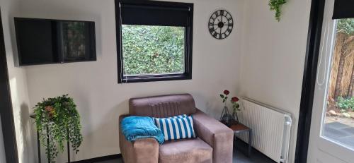 a living room with a chair and a television at Veluws Huisje in Apeldoorn