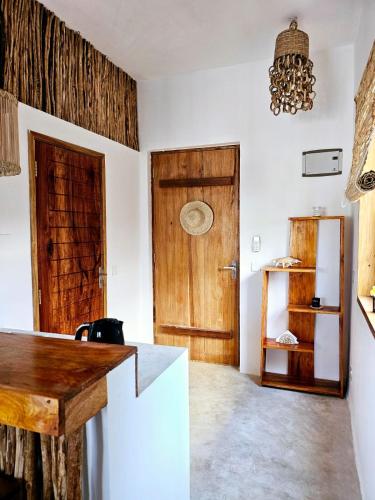 a kitchen with white walls and a wooden door at Mfumbwi Twins Apartments in Jambiani