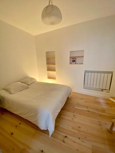 une chambre avec un lit blanc et un parquet dans l'établissement Appartement de charme au coeur du centre historique, à Bordeaux